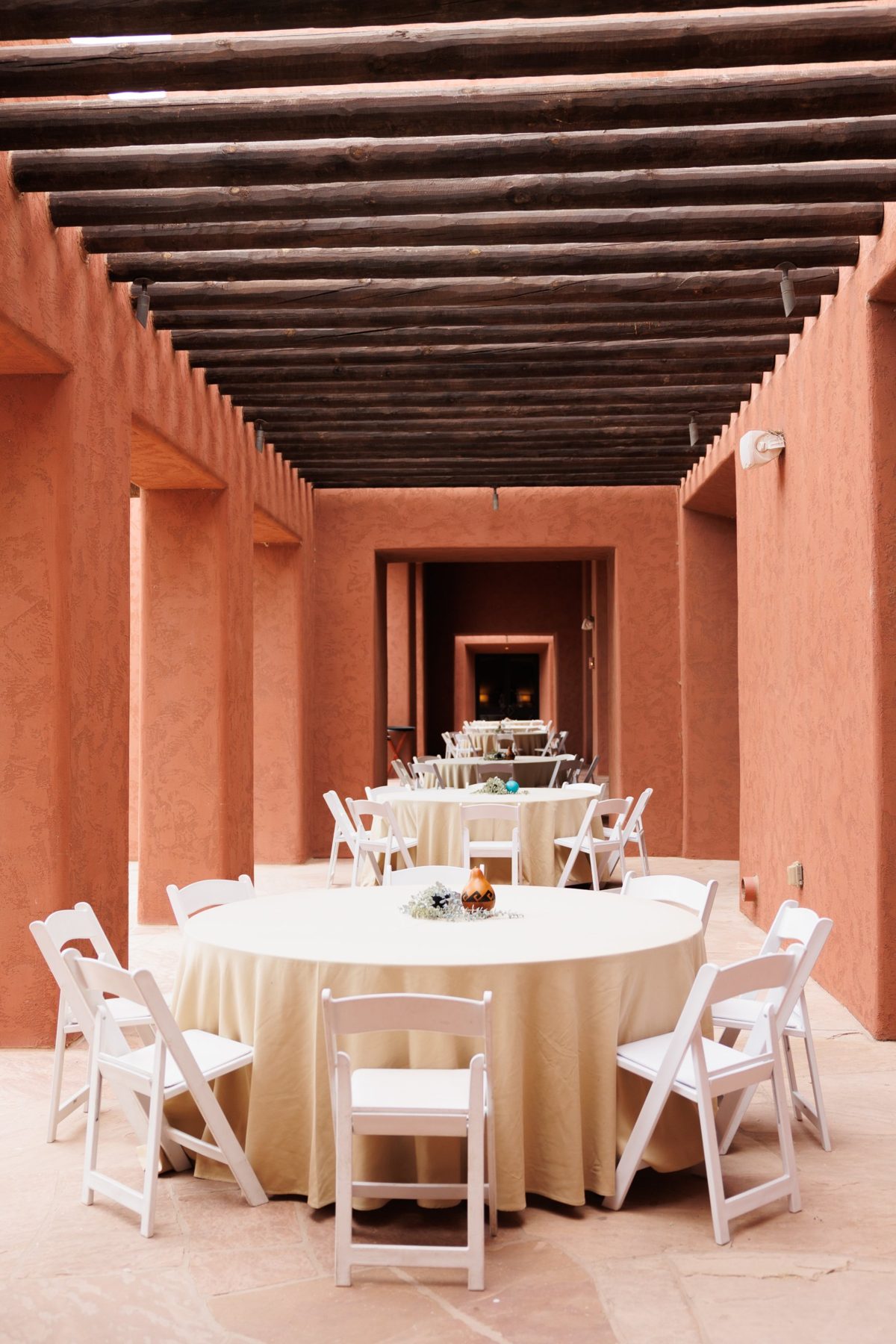 Round tables with cream linens under a wooden pergola