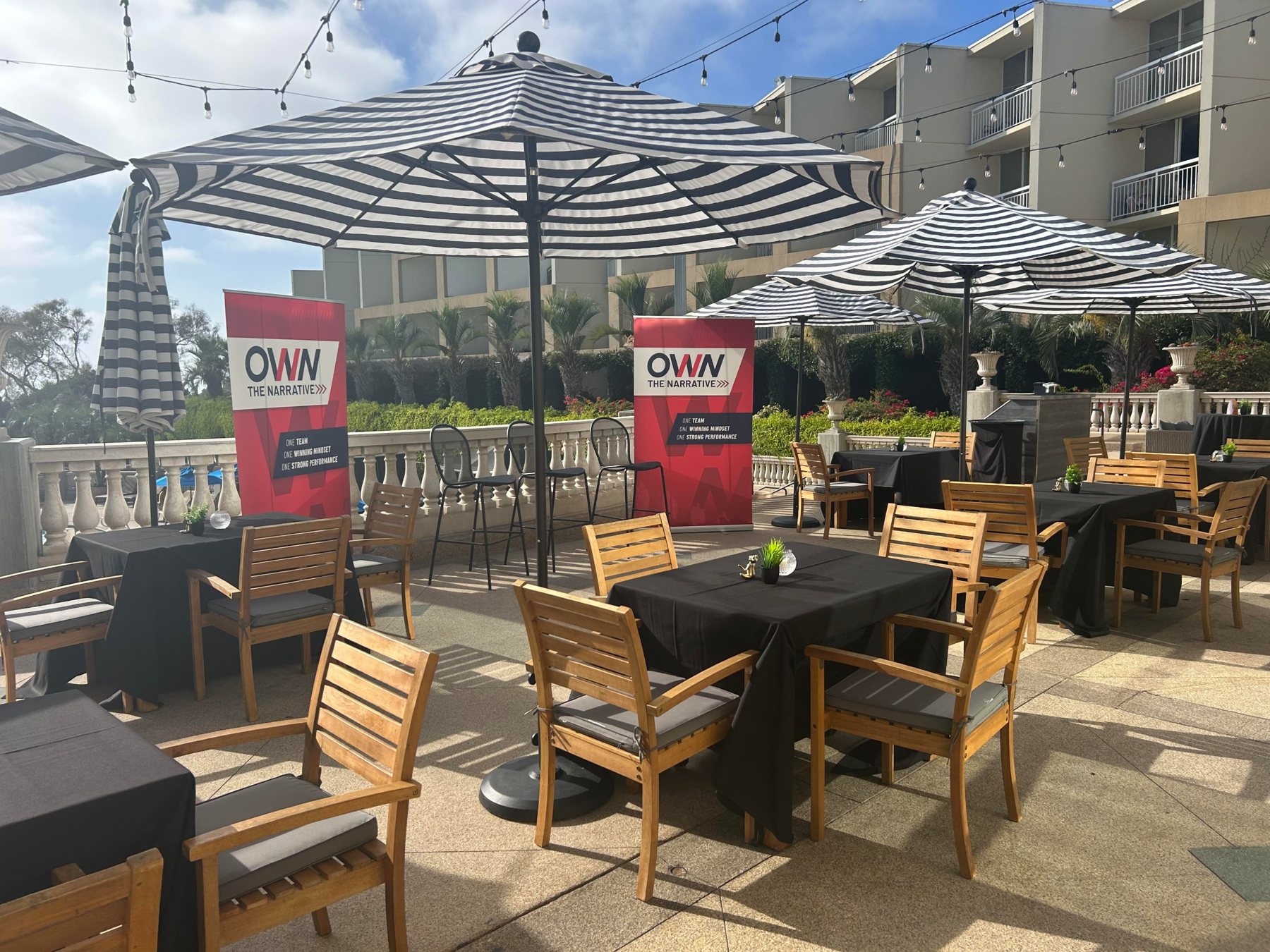 Outdoor terrace with striped umbrellas, black-linen tables and branded banners